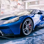 A blue sports car is washed in a garage