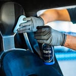 A man polishes a vehicle seat headrest with a bottle of Prima Nero