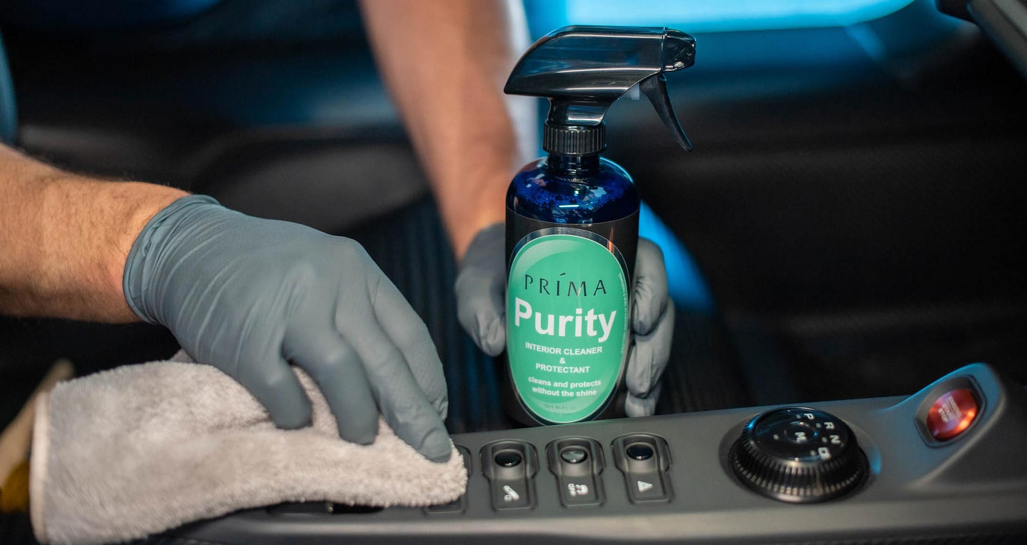 A bottle of Prima Purity interior cleaner and a man polishing a dashboard.