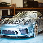 A soapy Porsche car sits in a garage