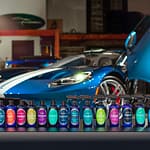 The full line of Prima Car Care products sit in a row in front of a blue sports car